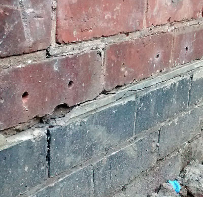 Chemical Damp Proof Course holes in a brick wall, just above the original slate DPC